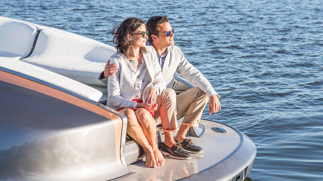Мъж и жена гледащи слънцето от Lexus яхта